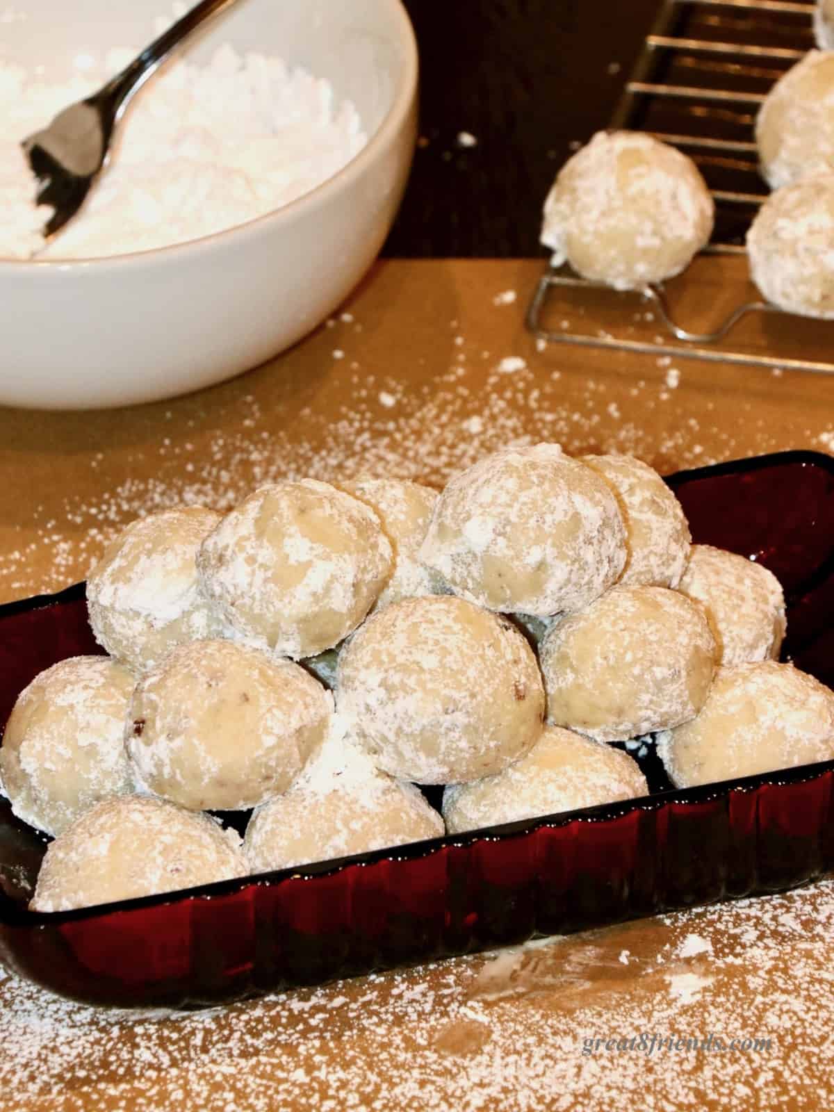 Bite Size Snowball cookies in a red glass dish with powdered sugar.