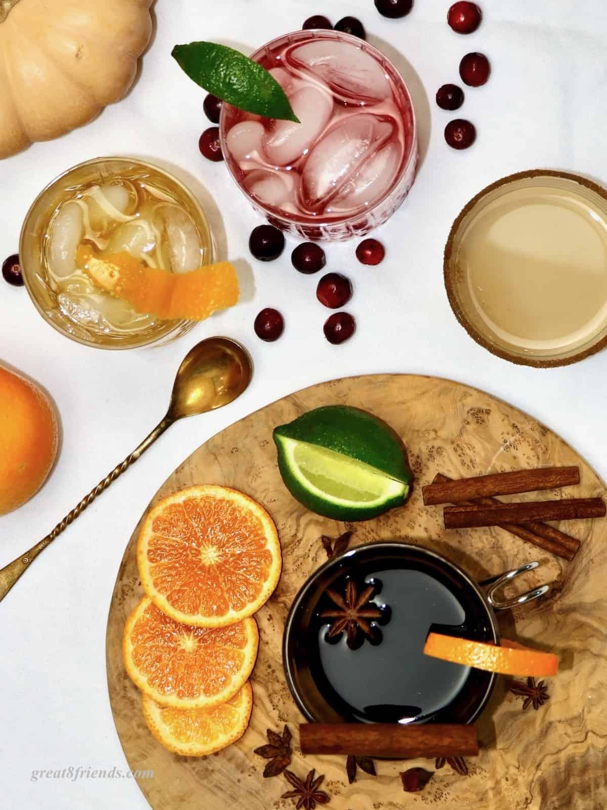 Overhead shot of a variety of fall cocktails with fruits and garnishes.