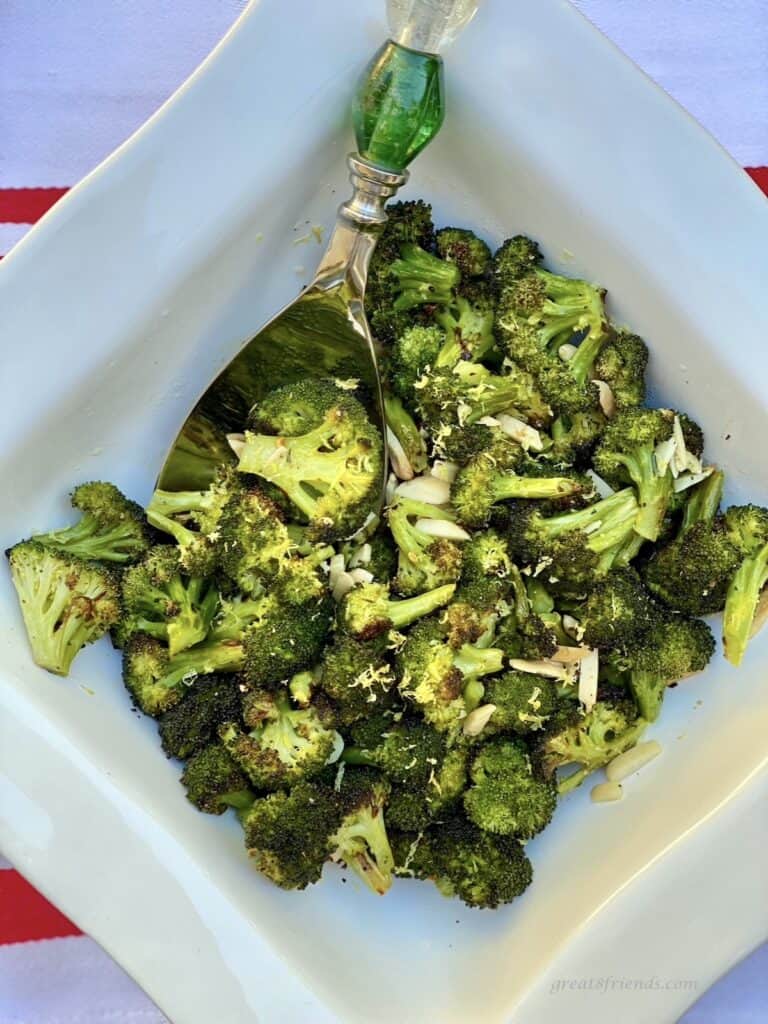 Oven baked broccoli being served in a white bowl.