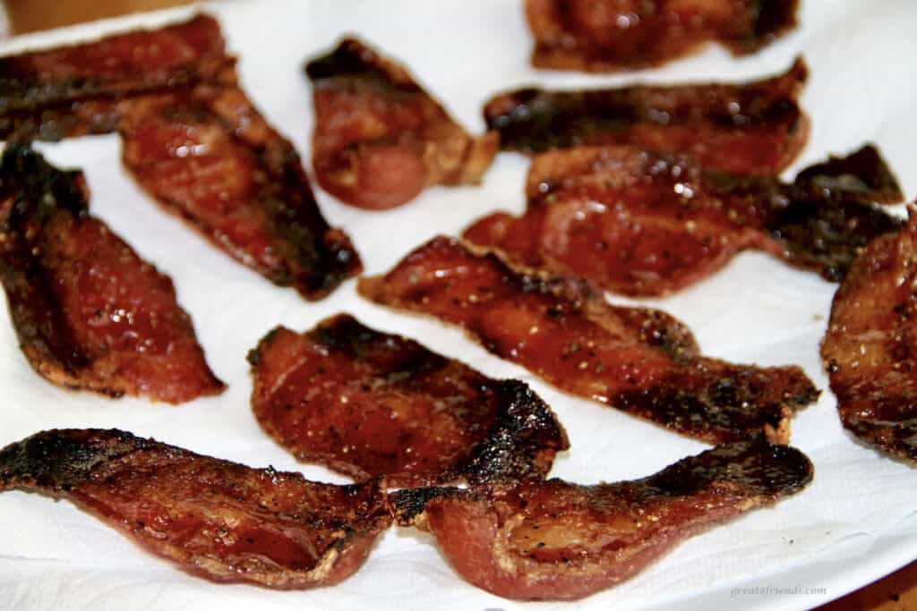 Pieces of bacon on a white plate.