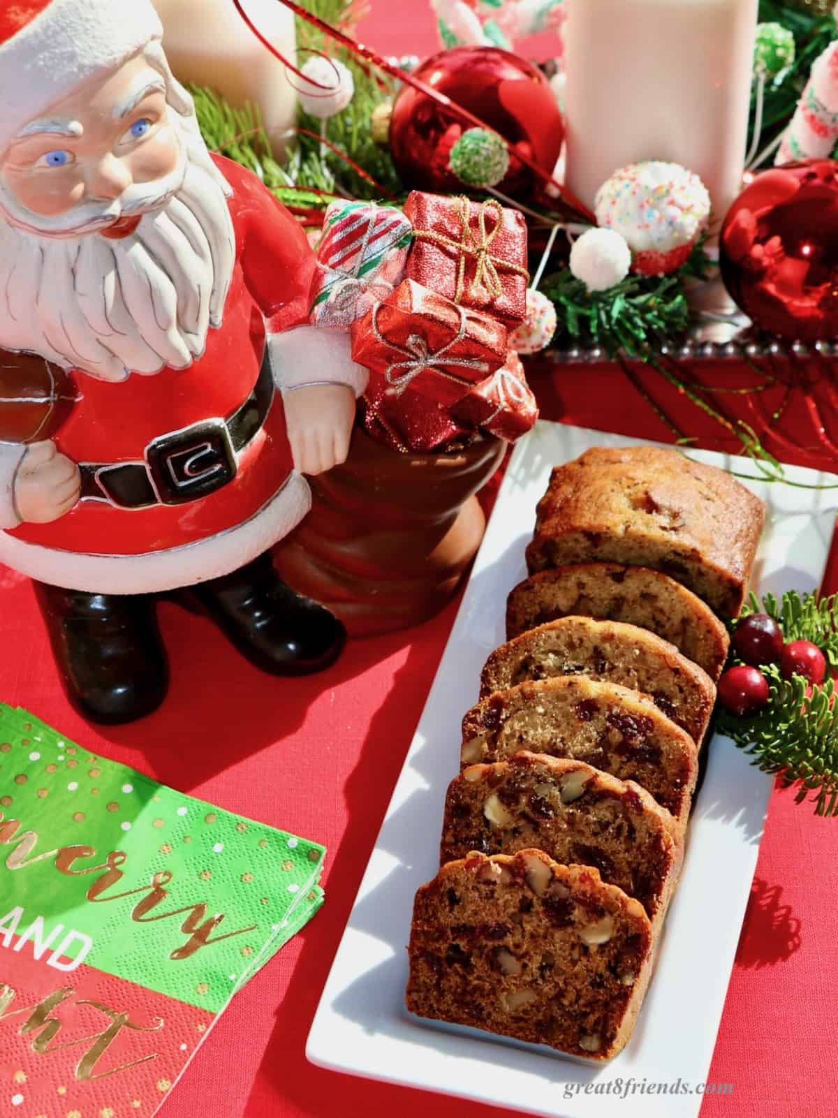 A rectangular plate of sliced Cranberry Date Nut Bread with a ceramic Santa.
