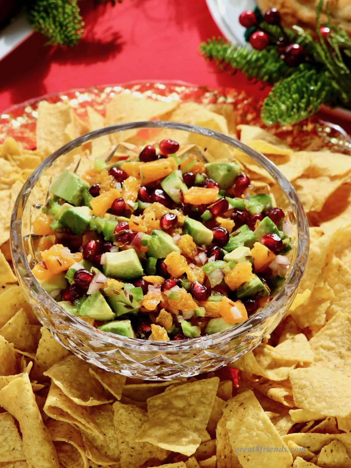 Pomegranate Avocado salsa in a crystal bowl surrounded by tortilla chips.