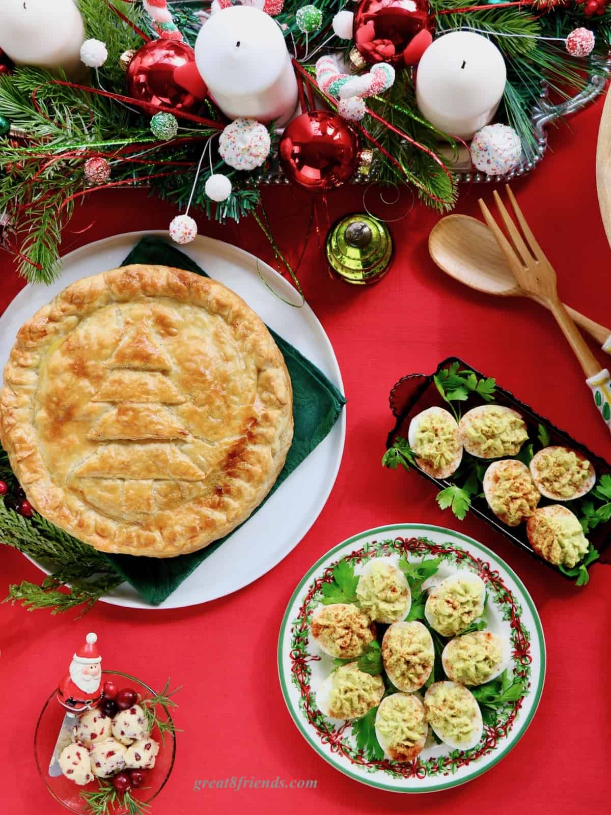 Overhead shot of brunch torte and deviled eggs on a red tablecloth with a Christmas centerpiece.