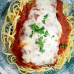 Overhead shot of Chicken Parma garnished with parsley.