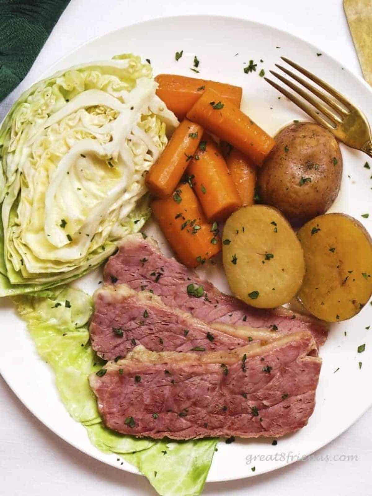 Dinner plate filled with sliced corned beef, a wedge of cabbage, potatoes and carrots.