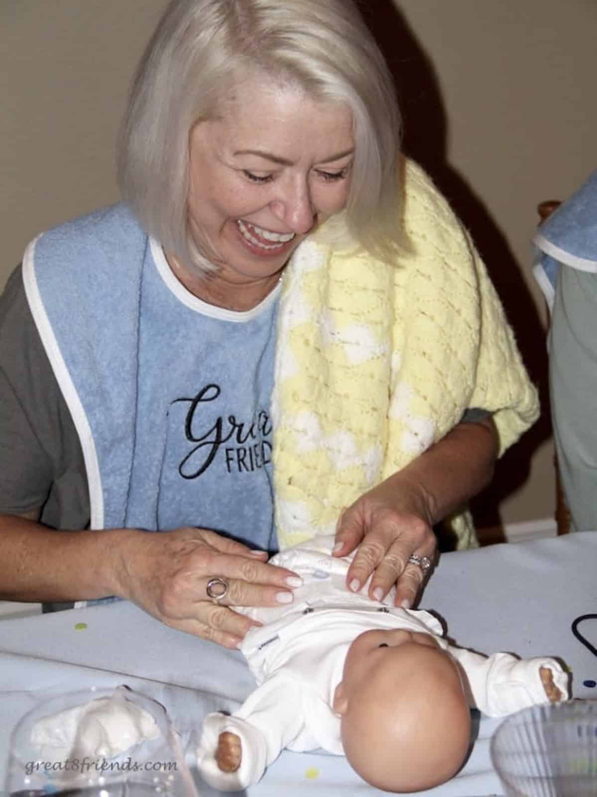 A woman putting a diaper on a baby doll on a table.
