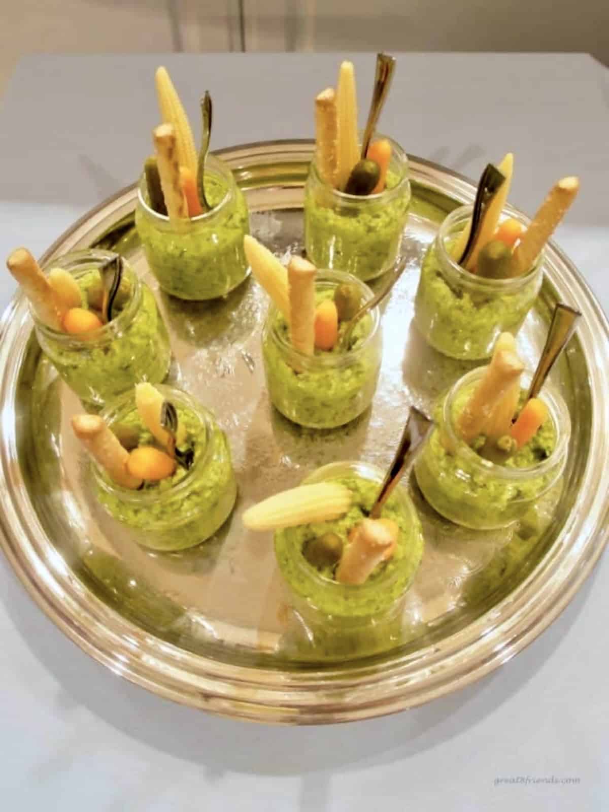 Vegetable dip being served in baby food jars with baby vegetables in each jar.