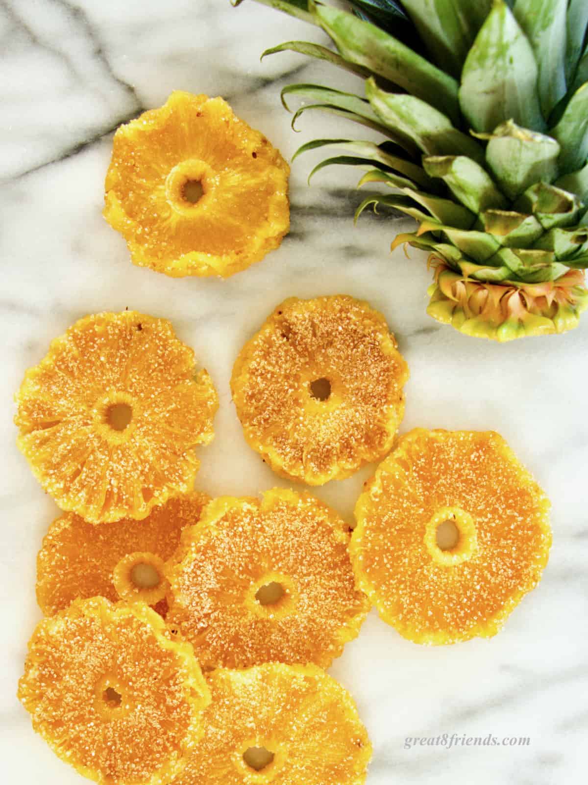 Candied pineapple slices laying on marble.