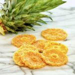 Candied pineapple slices laying on marble.