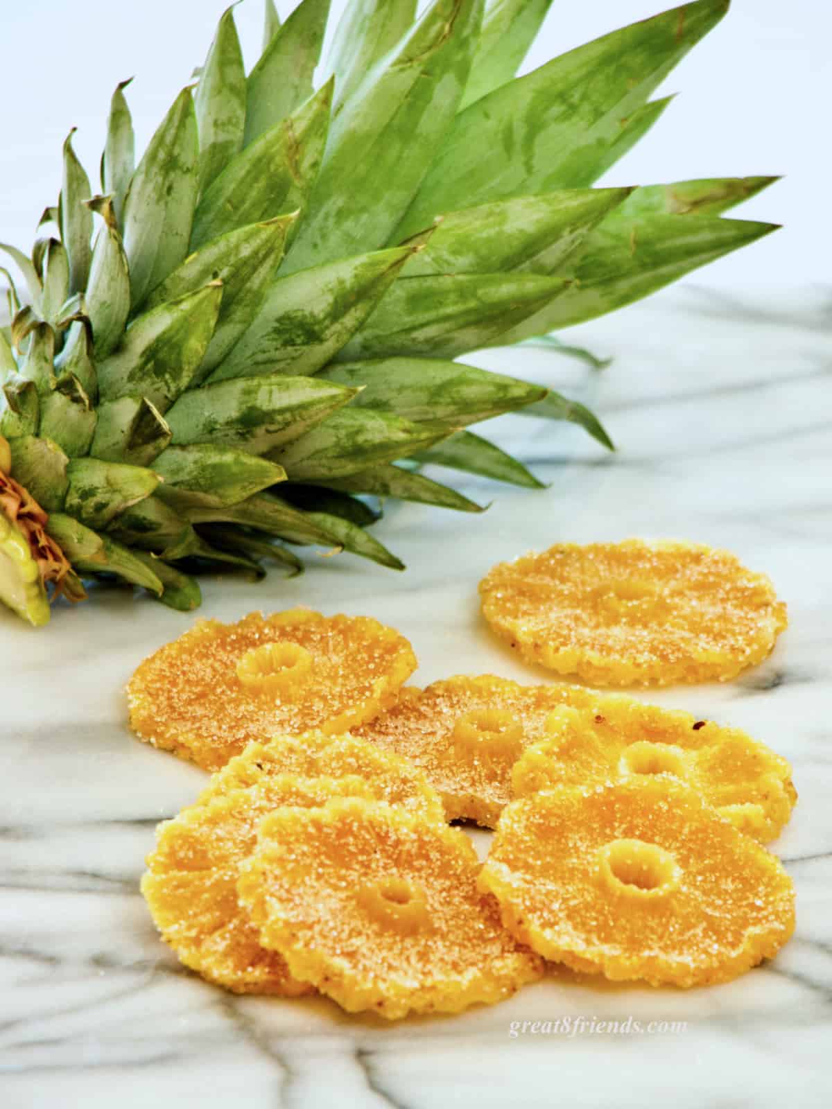 Candied pineapple slices laying on marble.
