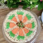 Overhead view of a round layered carrot cake decorated with icing carrots on the top.