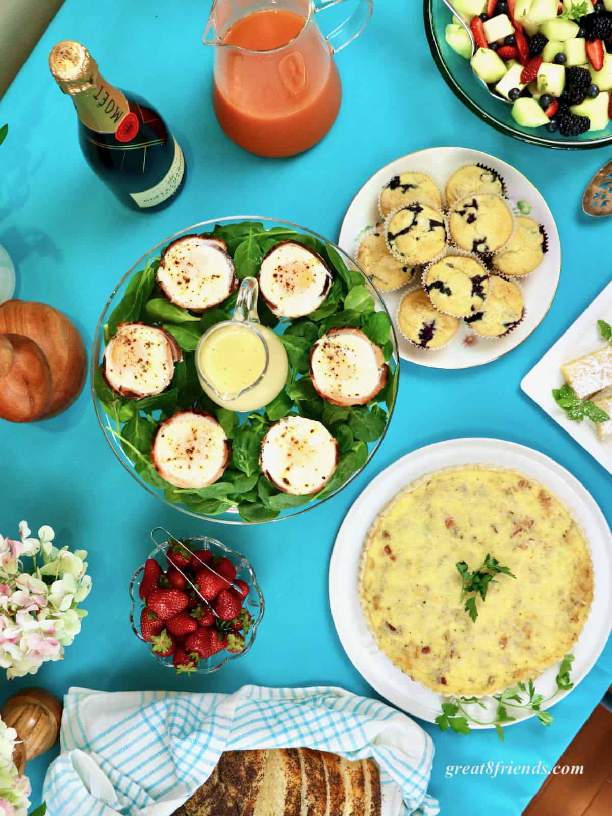 Overhead shot of an Easter brunch buffet table, eggs, muffins, quiche, strawberries.