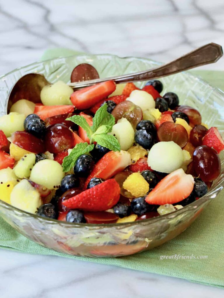 Fruit salad in a glass bowl on a green napkin.