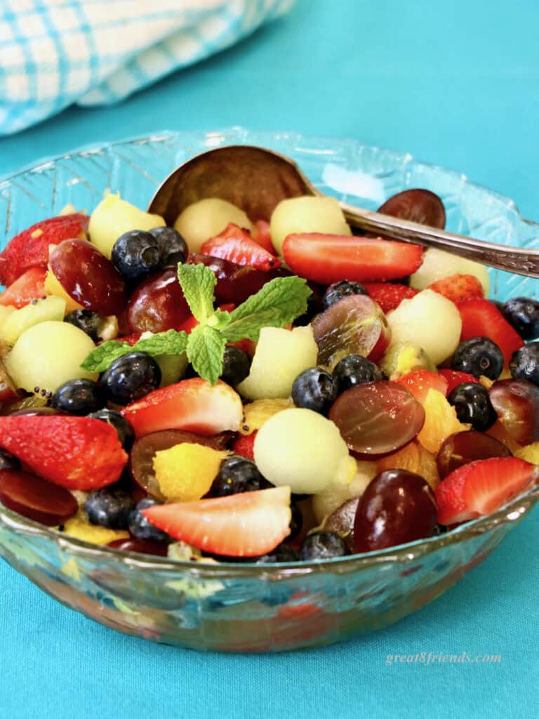 Fruit salad in a glass on a blue background.