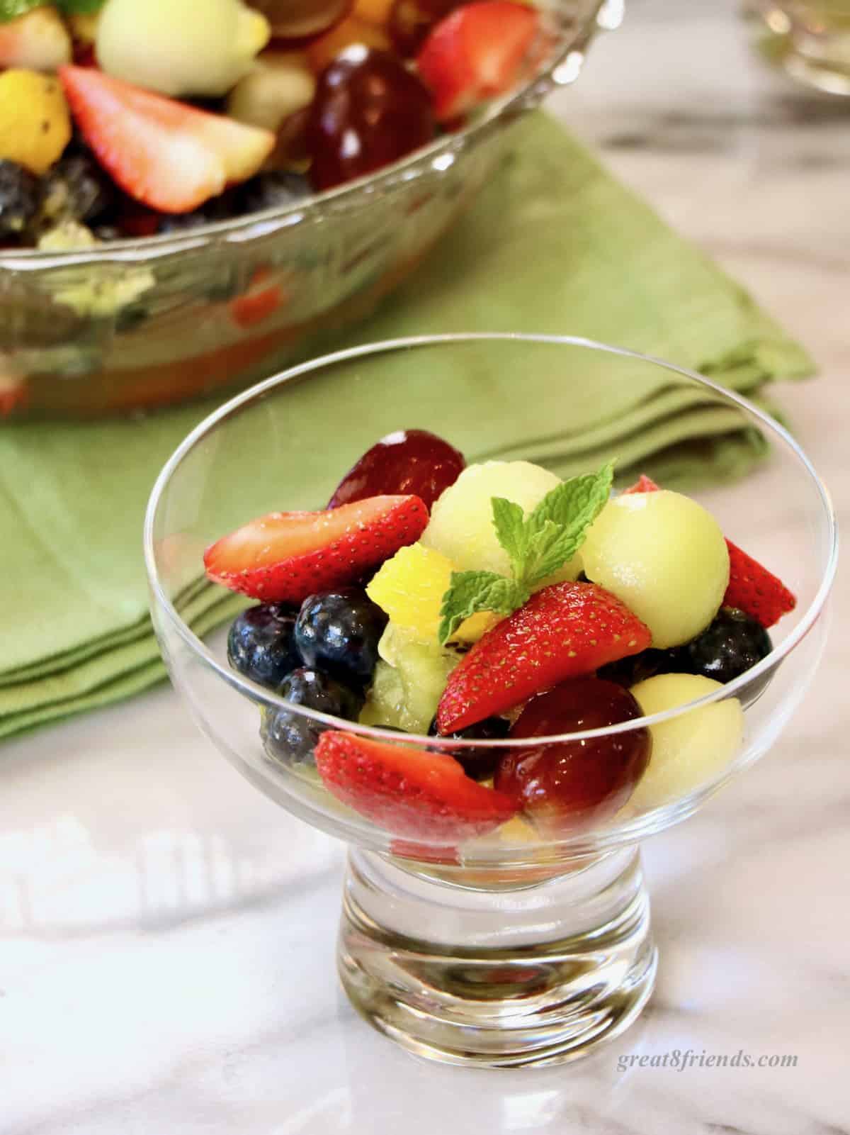 A single serving of fruit salad in a footed glass bowl.