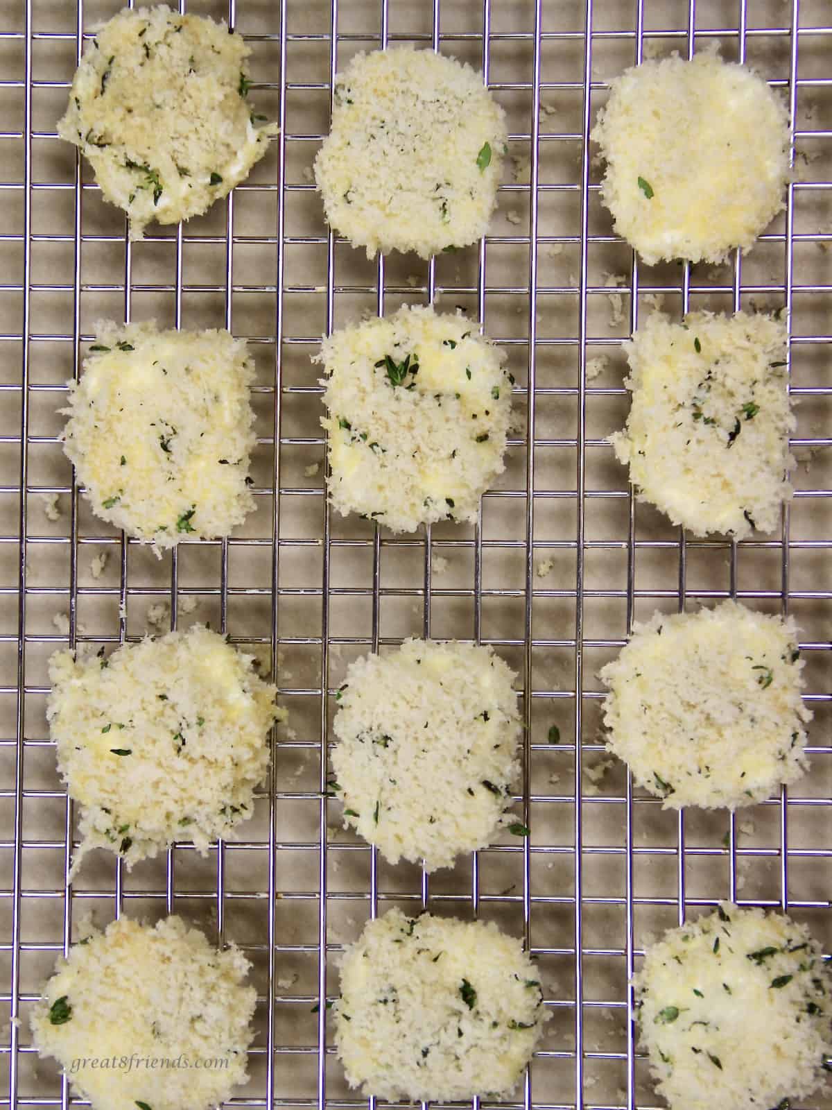 Baking rack with goat cheese rounds covered with bread crumbs and thyme.
