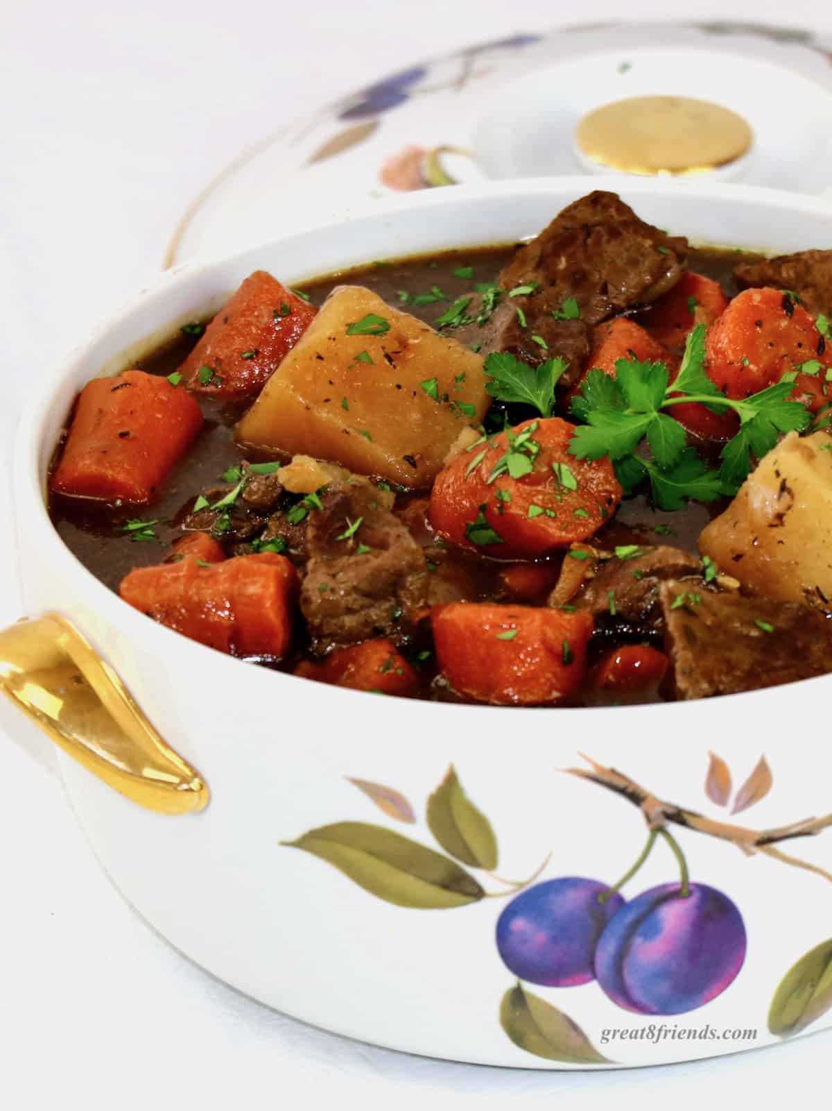 Beef stew in a ceramic casserole decorated with fruit.
