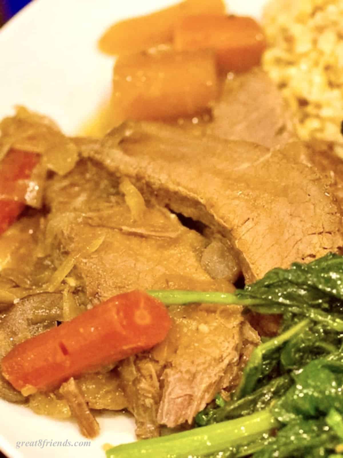 Upclose photo of a plate with brisket, fried corn, and Broccoli Rabe.