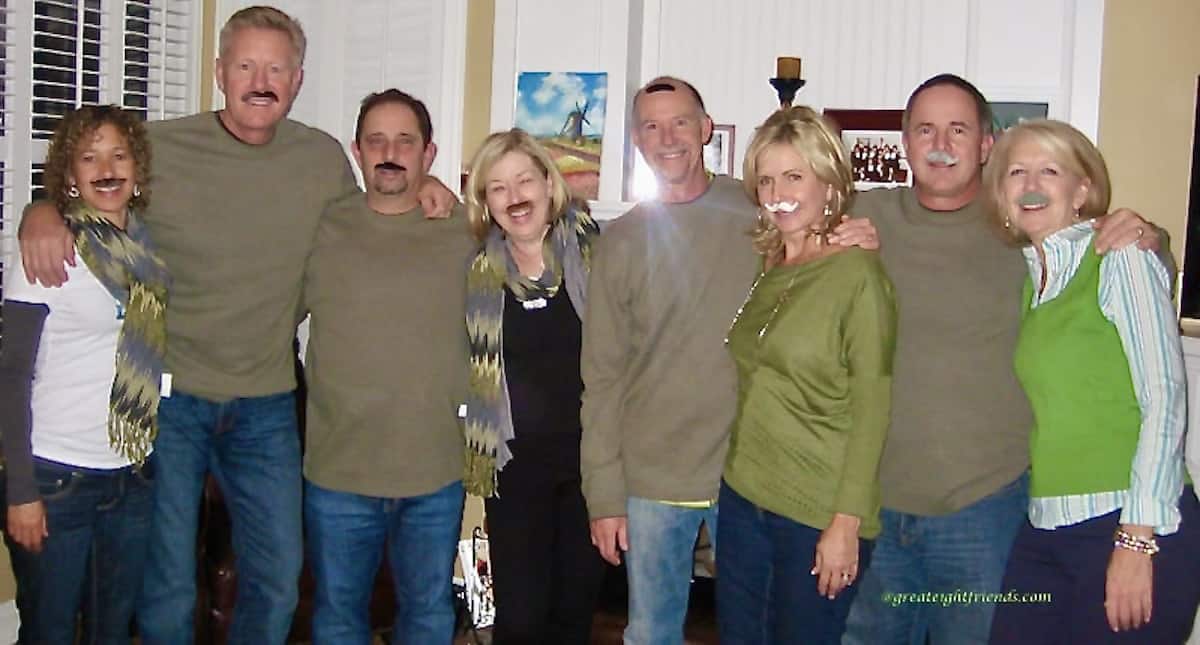 Group of eight people posing for the camera with fake mustaches on.