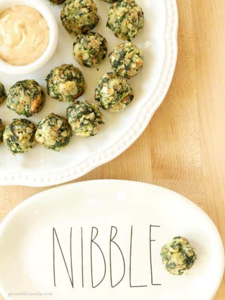 Spinach Balls being served with a sauce and one spinach ball in a plate that says, "nibble."